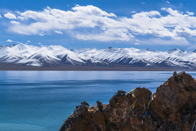 Scenic view of sea and snowcapped mountains against sky