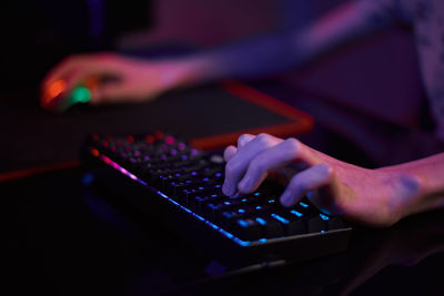 Gamer play computer game, use rgb neon colored keyboard