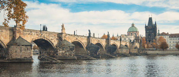 Bridge over river against cloudy sky