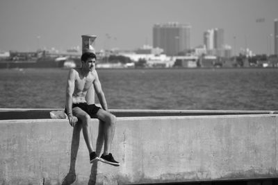 Full length of shirtless man in sea against sky