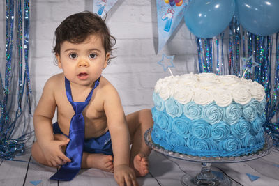 Portrait of cute boy sitting at home in smash cake 