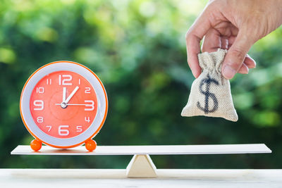 Close-up of hand holding clock against blurred background