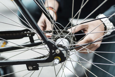 Cropped image of businessman repairing bicycle tire on street