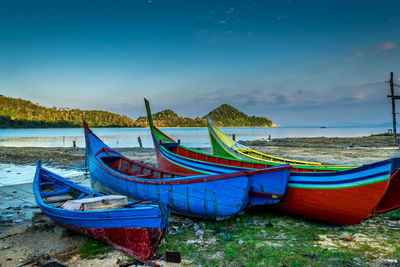 Boat moored on beach against sky