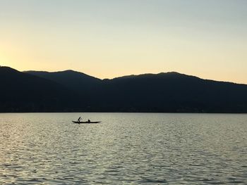 Silhouette boat in lake against sky during sunset