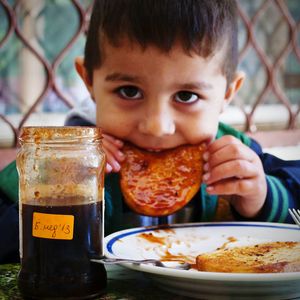 Portrait of cute boy eating food while sitting at table