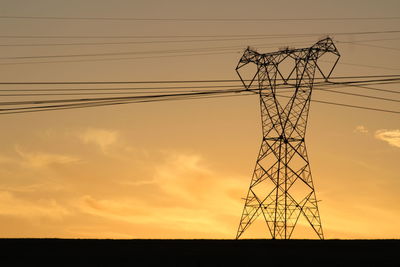 Low angle view of silhouette electricity pylon against sky during sunset