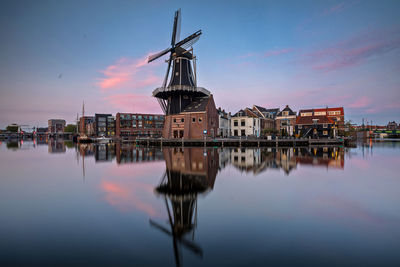 View of windmill by river against sky