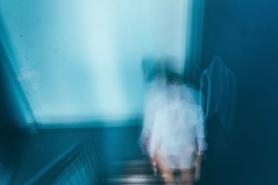 Blurred motion image of man walking down steps by blue wall