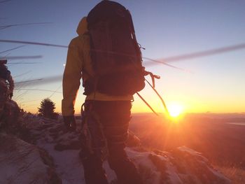 Rear view of hiker on snow covered mountain during sunset
