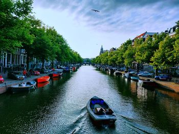 Boats moored in canal against sky in city