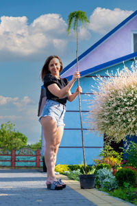 Full length of young woman standing against trees