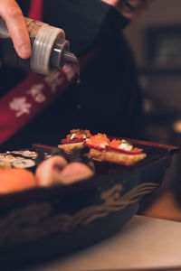 Cropped hand of person preparing sushi on table