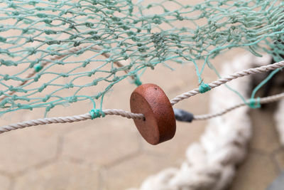 Close-up of rope tied on metal fence against wall