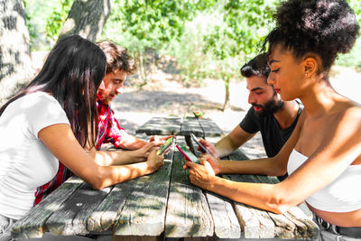Friends using smart phones sitting outdoors