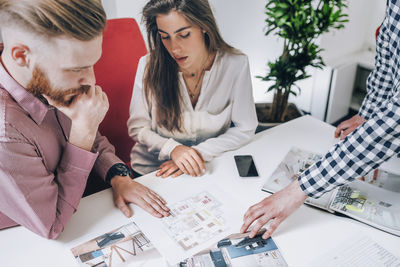 Young couple discussing over document while real estate agent explaining 