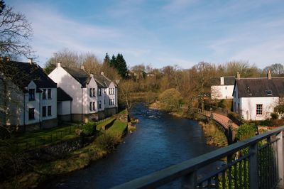 River amidst houses and buildings against sky