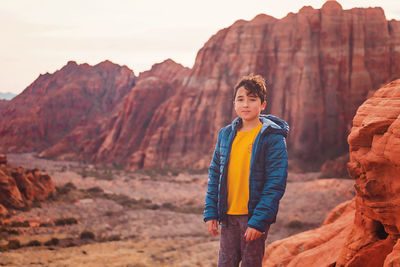 Boy hiking on trail by the red sandstone cliffs and mountains in utah