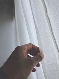 Close-up of person holding curtain at home