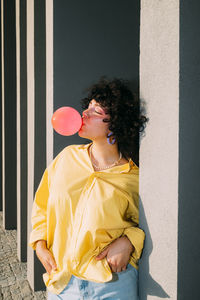 Woman with hands in pockets blowing bubble gum on sunny day