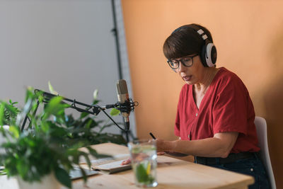 Woman wearing headphones sitting against wall