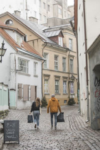 Rear view of women walking on street amidst buildings