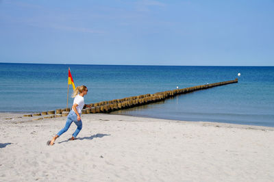 Young woman running on sand against sea at beach