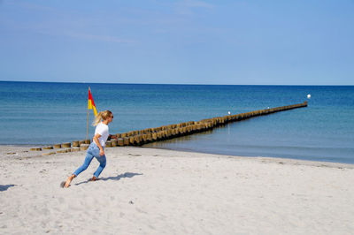 Full length of woman running on beach against sky