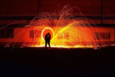 Full length of woman standing against illuminated lights at night