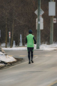 Rear view of man walking on snow covered road