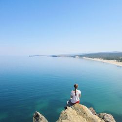 Woman sitting on rock over sea