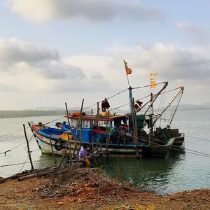 Fishing boats moored on sea against sky