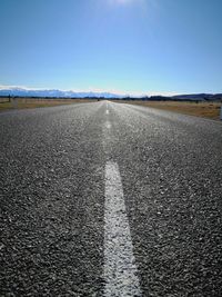 Surface level of road against clear blue sky