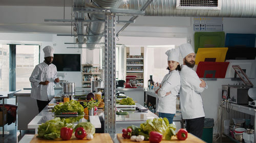 Portrait of chefs standing back to back in kitchen