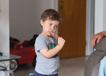 Cute toddler is brushing his teen in the livingroom