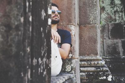 Thoughtful handsome man sitting on old ruin building wall