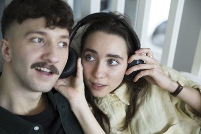 Heterosexual couple listening music through headphones at home