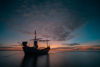 Silhouette of sailboat in sea against sky during sunset