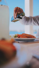 Cropped hand pouring oil on salad