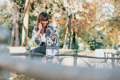 Side view of young woman sitting on railing