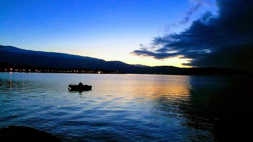 Silhouette boat in lake against sky during sunset