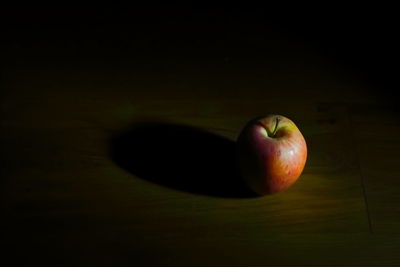 Close-up of apple on table against black background