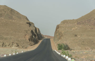 Road amidst mountains against clear sky