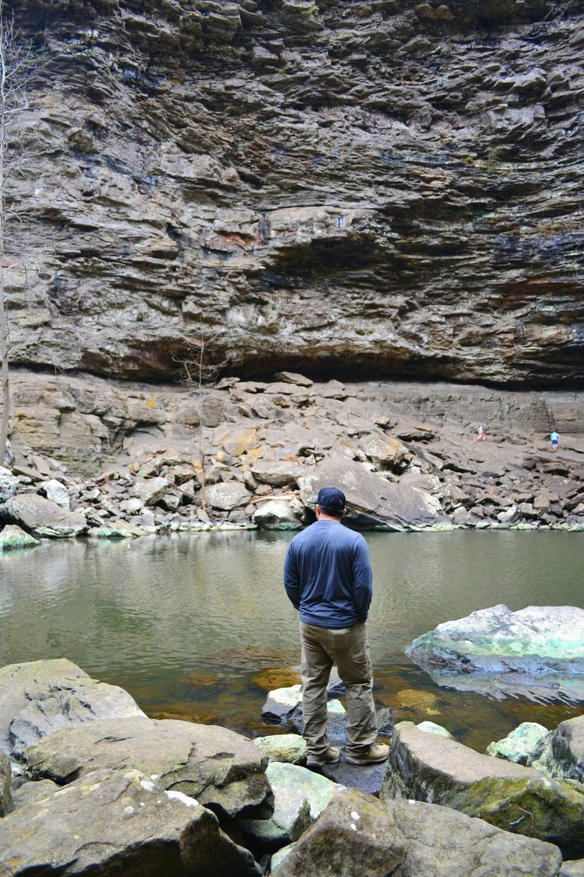 water, rear view, lifestyles, rock - object, leisure activity, full length, standing, men, casual clothing, rock, rock formation, nature, sea, person, sitting, lake, beauty in nature, childhood