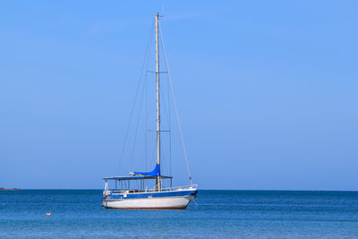 Ship sailing on sea against clear blue sky