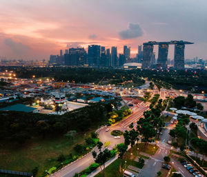 Aerial view of street amidst modern buildings against sky during sunset