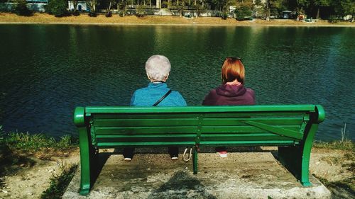 Rear view of people sitting on bench in park