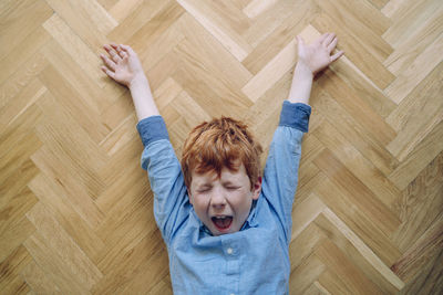 High angle view of boy lying on hardwood floor