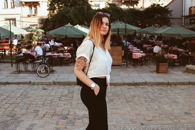 Portrait of beautiful woman standing on footpath