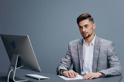 Portrait of young man using laptop at office